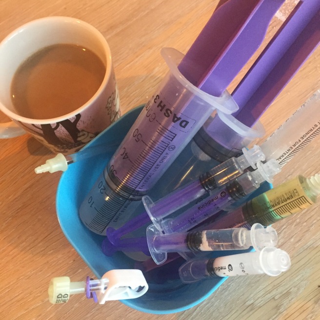 En kaffekopp og en plastboks med medisinsprøyter